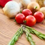 red tomatoes near rosemary and other spices close up photography