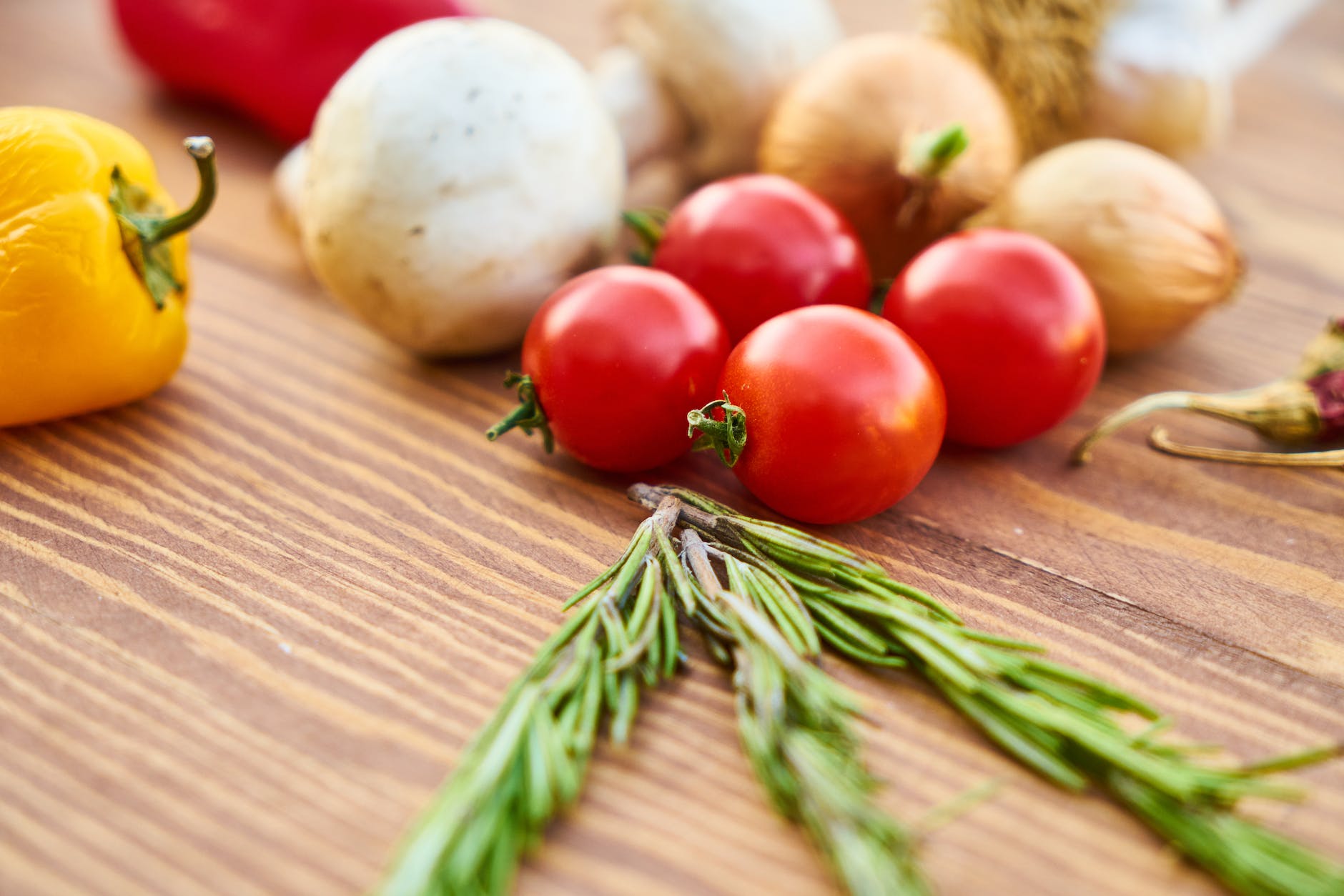 red tomatoes near rosemary and other spices close up photography